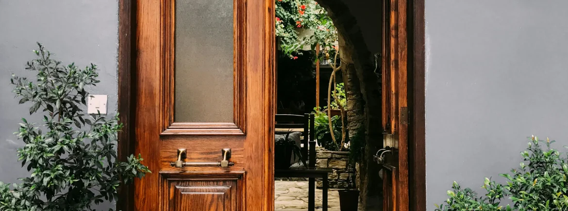 Brown front door with plants surrounding the door way.